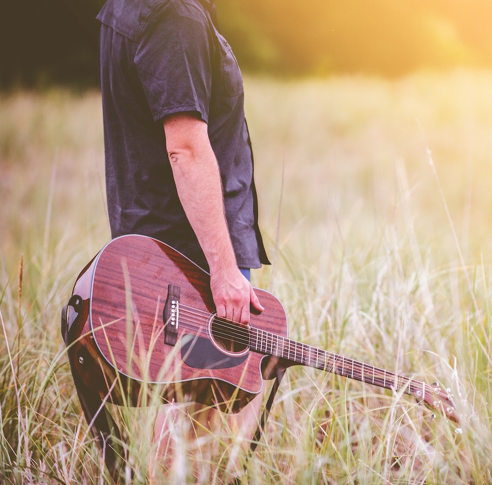 man with guitar in field